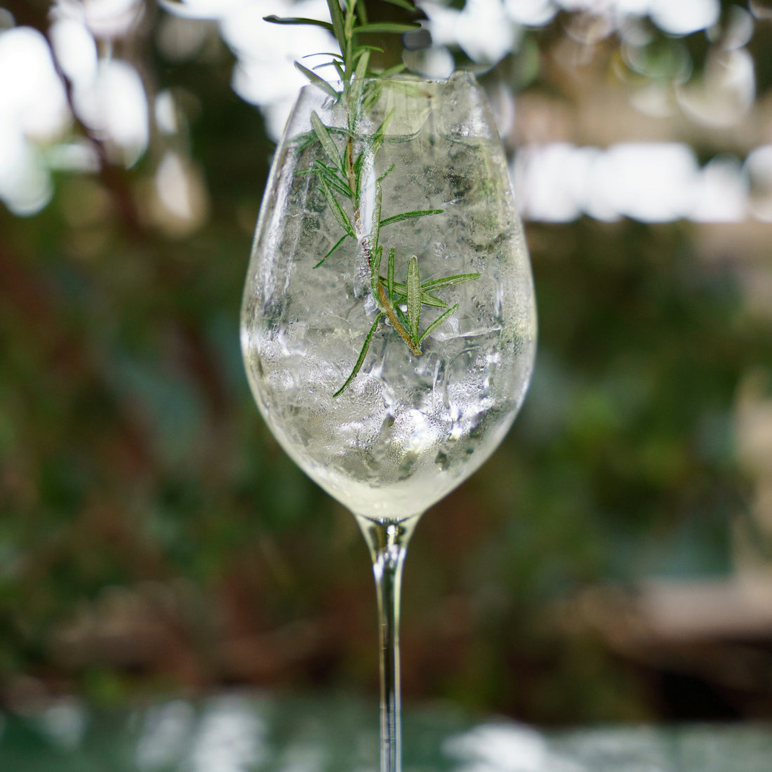 Spritz in a wine glass with ice and a sprig of rosemary