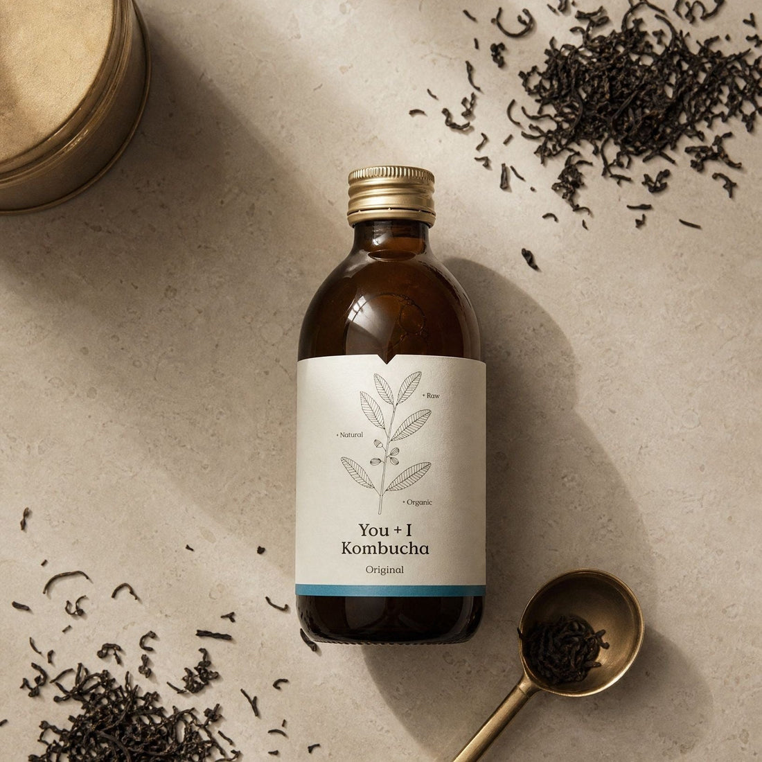 Bottle of You + I Original kombucha surrounded by loose whole leaf tea