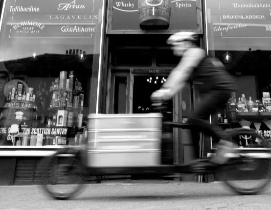 A cargo bike carrying a You + I delivery past a Glasgow shop front