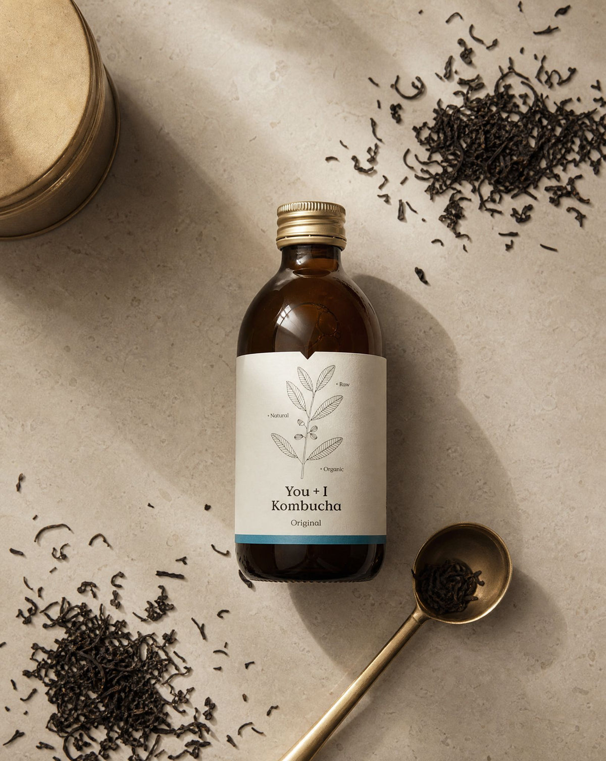 Bottle of You + I Original kombucha surrounded by loose whole leaf tea